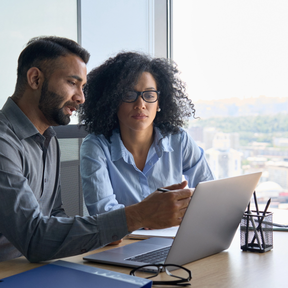 A consultant and a client huddle around a laptop as the consultant explains important information