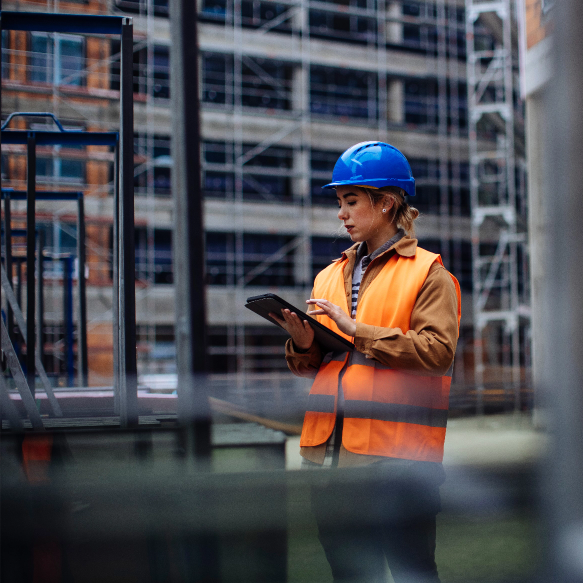 Getting the job done right: contact us for your specific needs A construction worker consults a tablet while overlooking a project